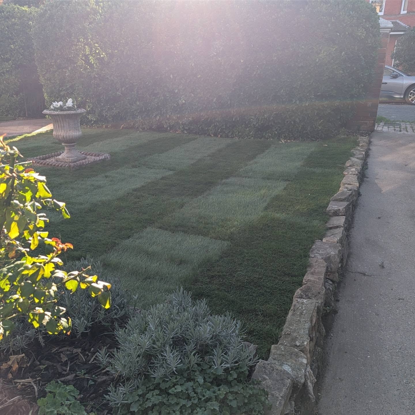 Landscaped front garden with lawn, stone edging and planters